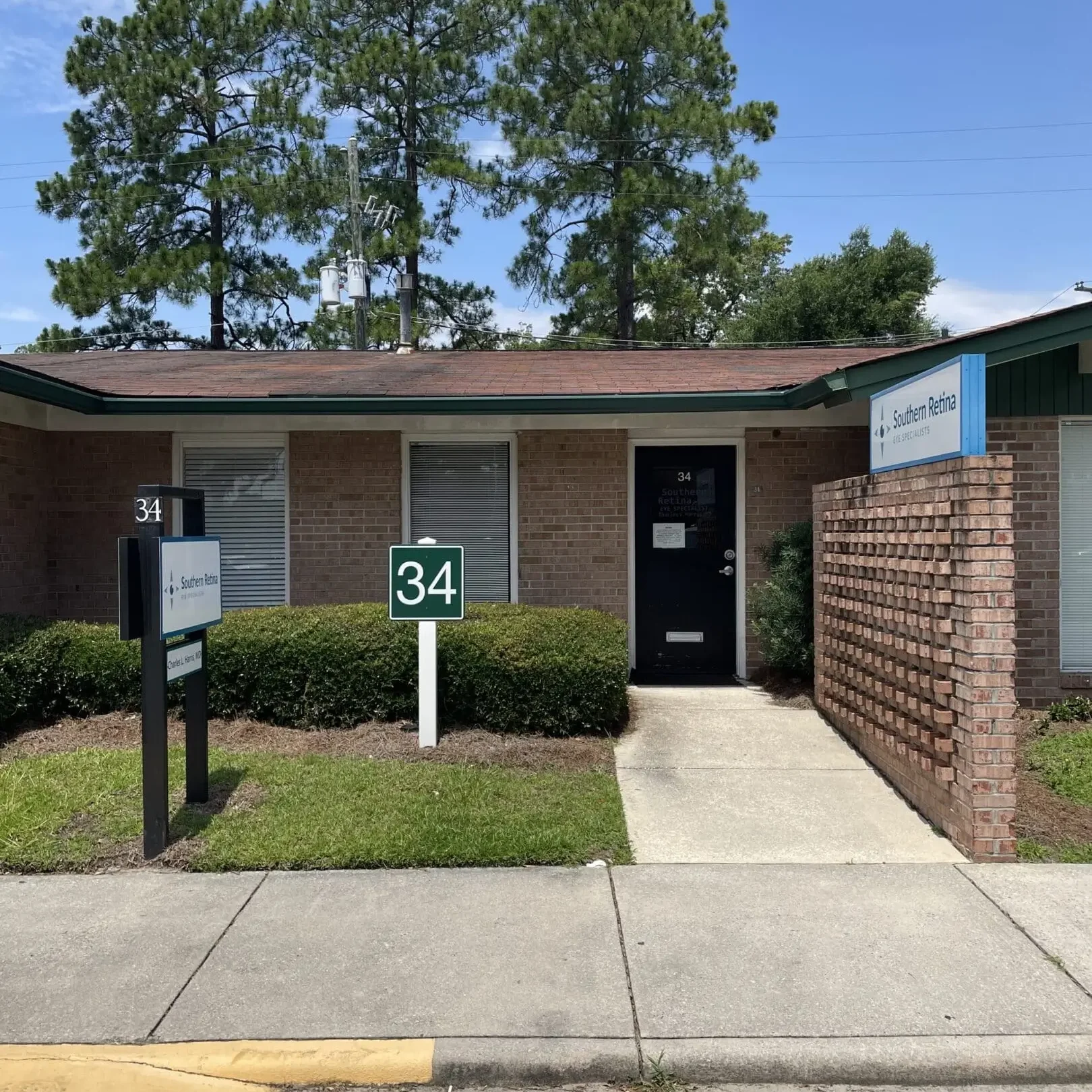 Single-story brick house with a black door and number 34 on a green sign.